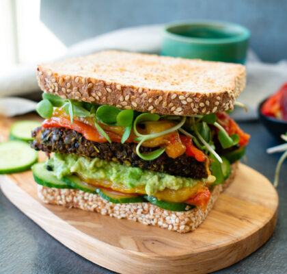Tempeh sandwich on sesame seed bread with avocado spread
